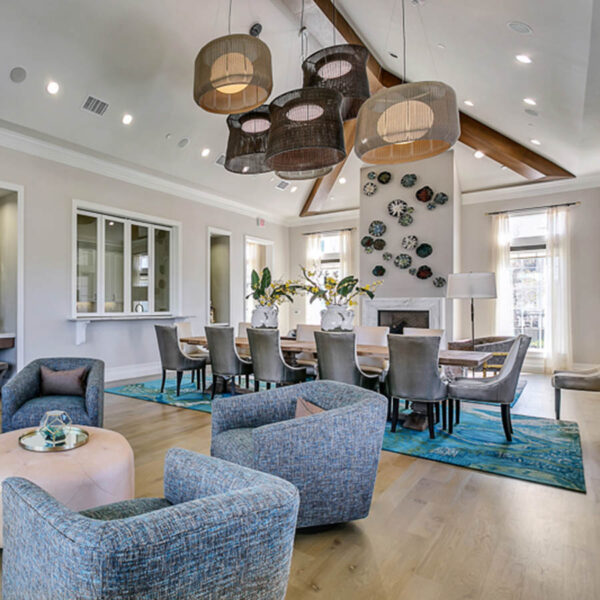 Clubroom with plush seating, large dining table, fireplace, and large elegant light fixtures.