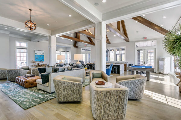 Lounge with community kitchen, pool table, plush seating, and vaulted ceilings.