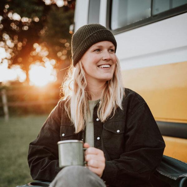 Person sitting outside with coffee at sunrise.
