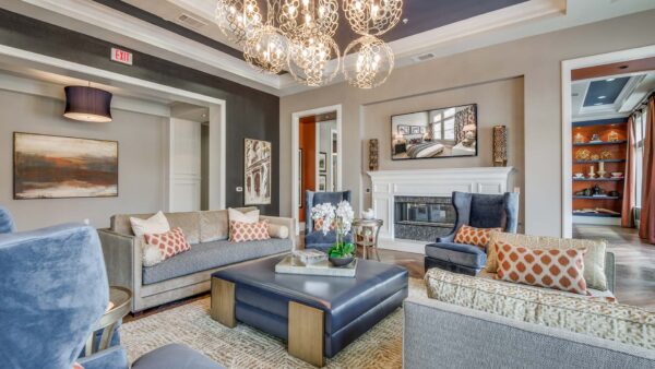 Shared community space with plush seating and upscale chandelier at The Kathryn apartments for rent in Frisco, TX.